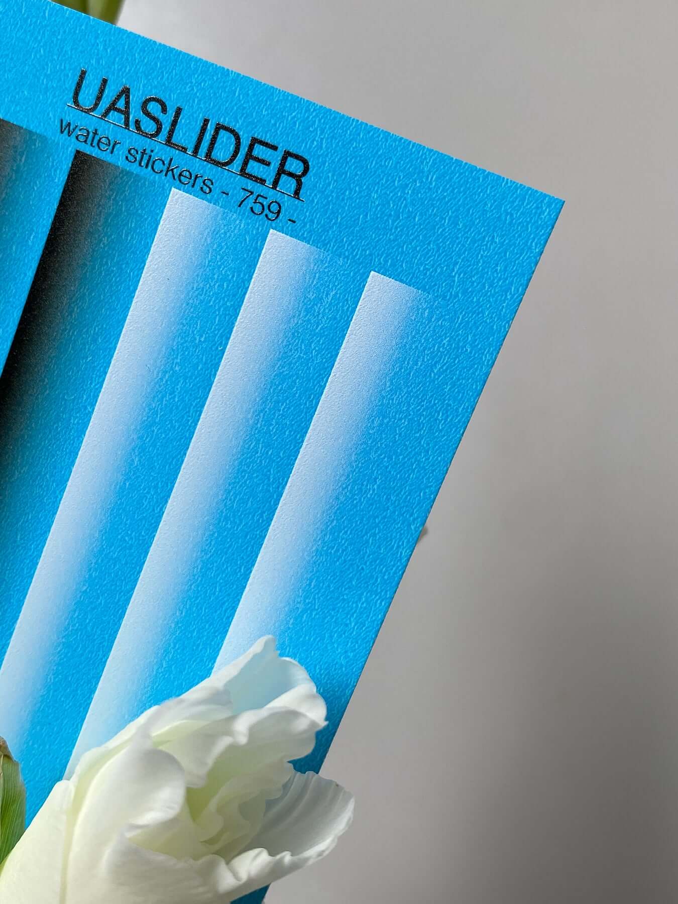 Nail Water Decal 759 on a blue sheet with white floral elements, displaying vivid water slide design features.